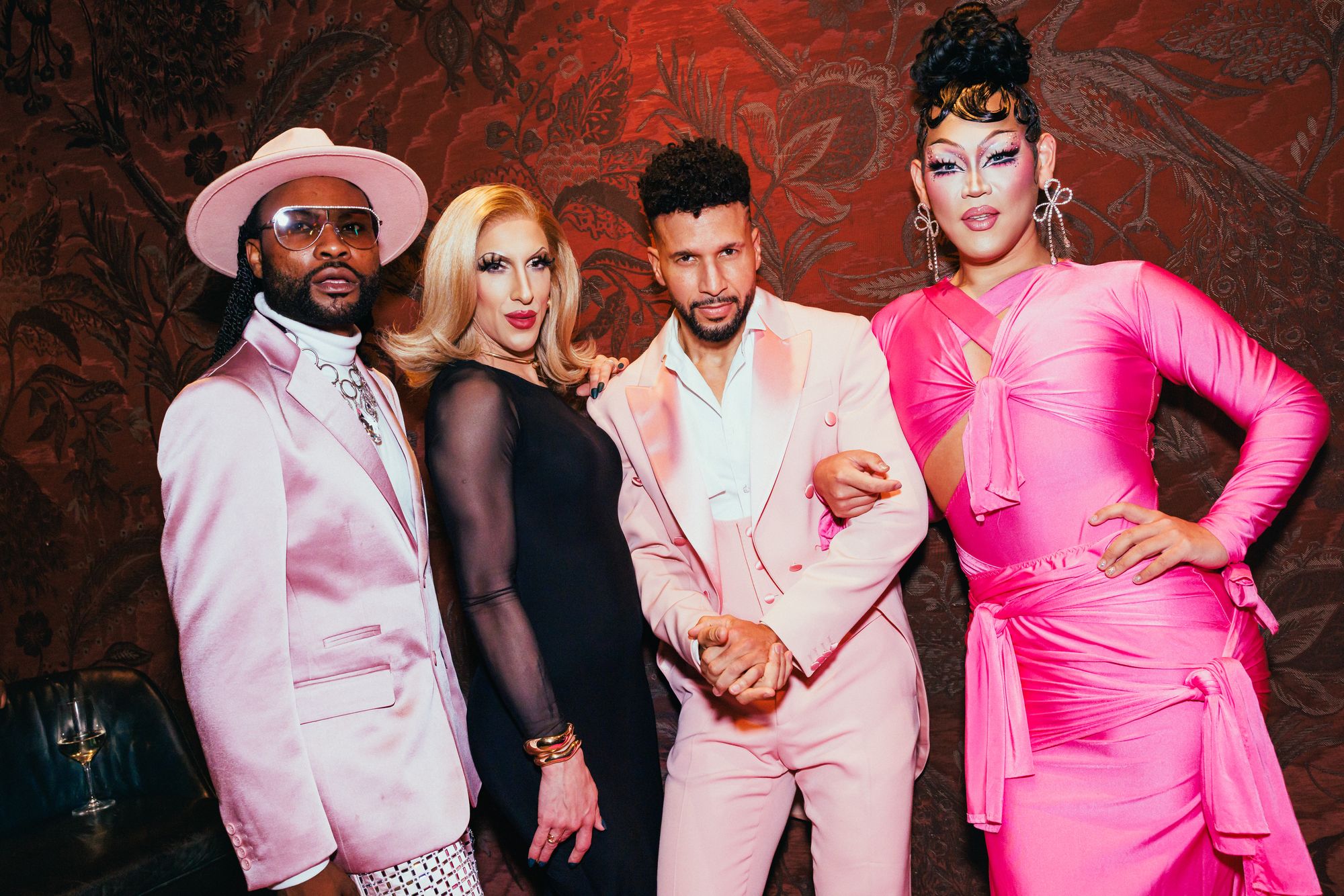 Four performers in coordinated pink and black formalwear pose together at an event