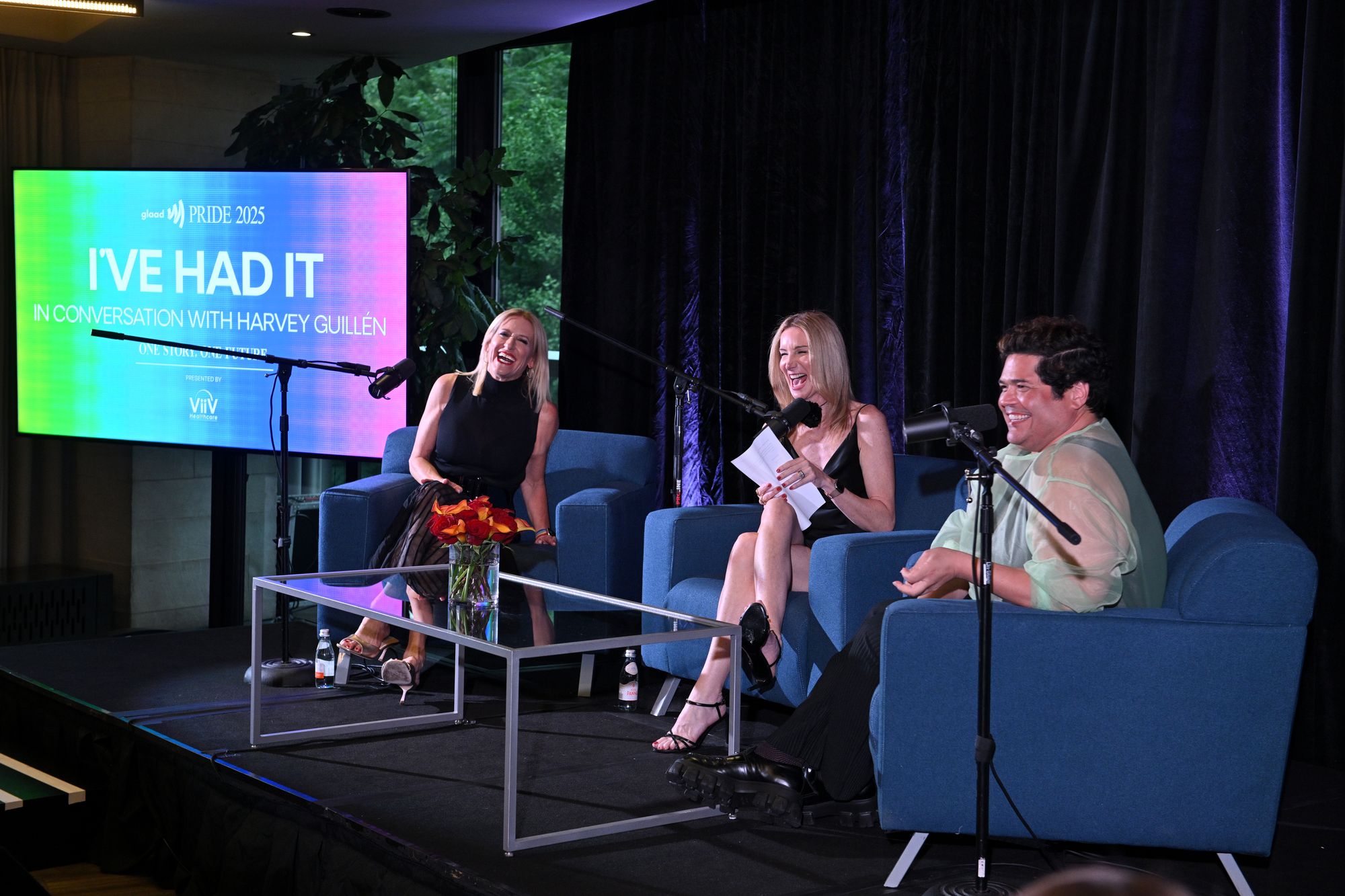 Three guests share a laugh on stage during a GLAAD Pride panel conversation
