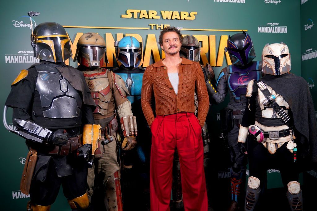 Pedro Pascal poses with costumed Mandalorian characters at a Star Wars premiere step-and-repeat