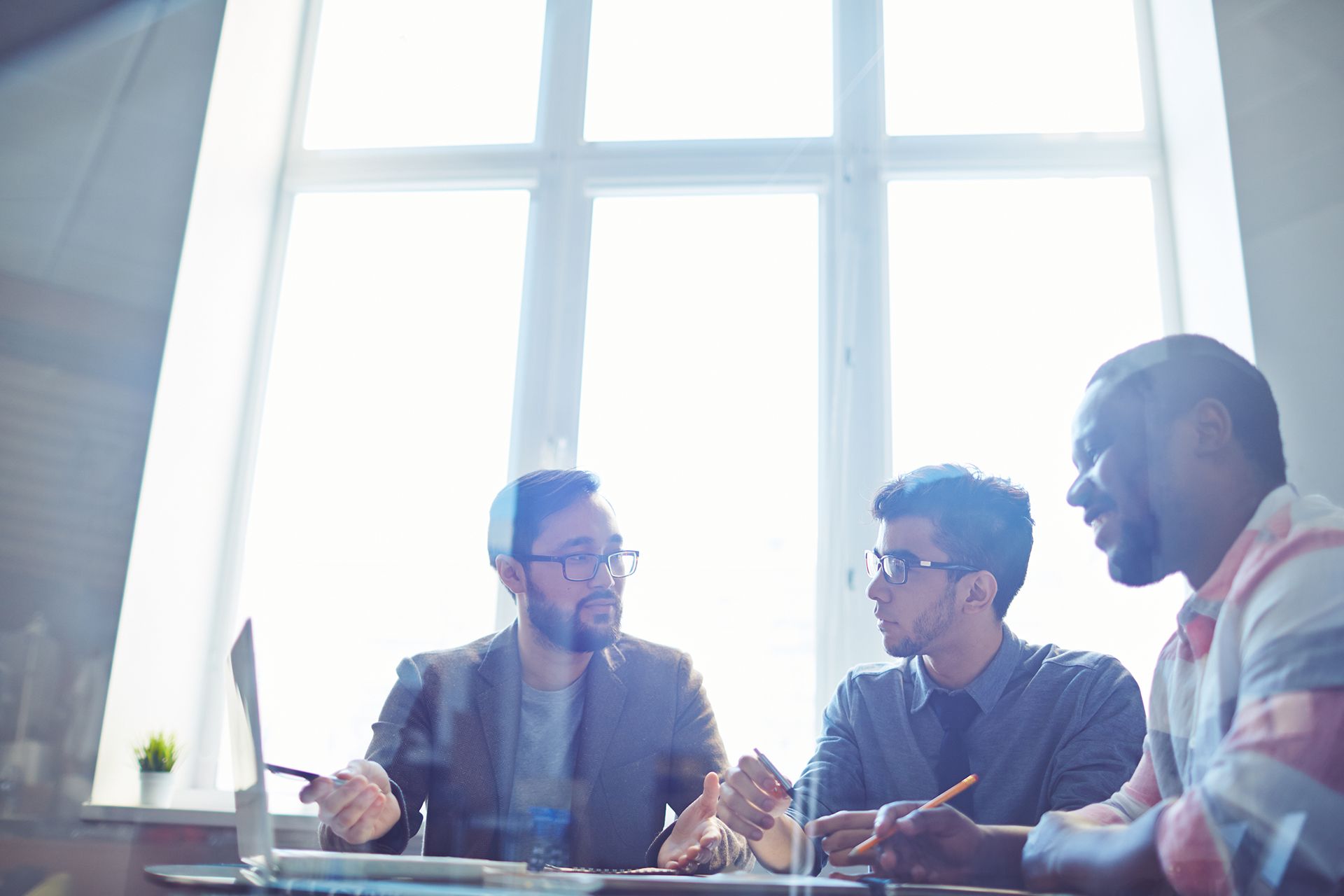 A team meets at a table in front of a bright window