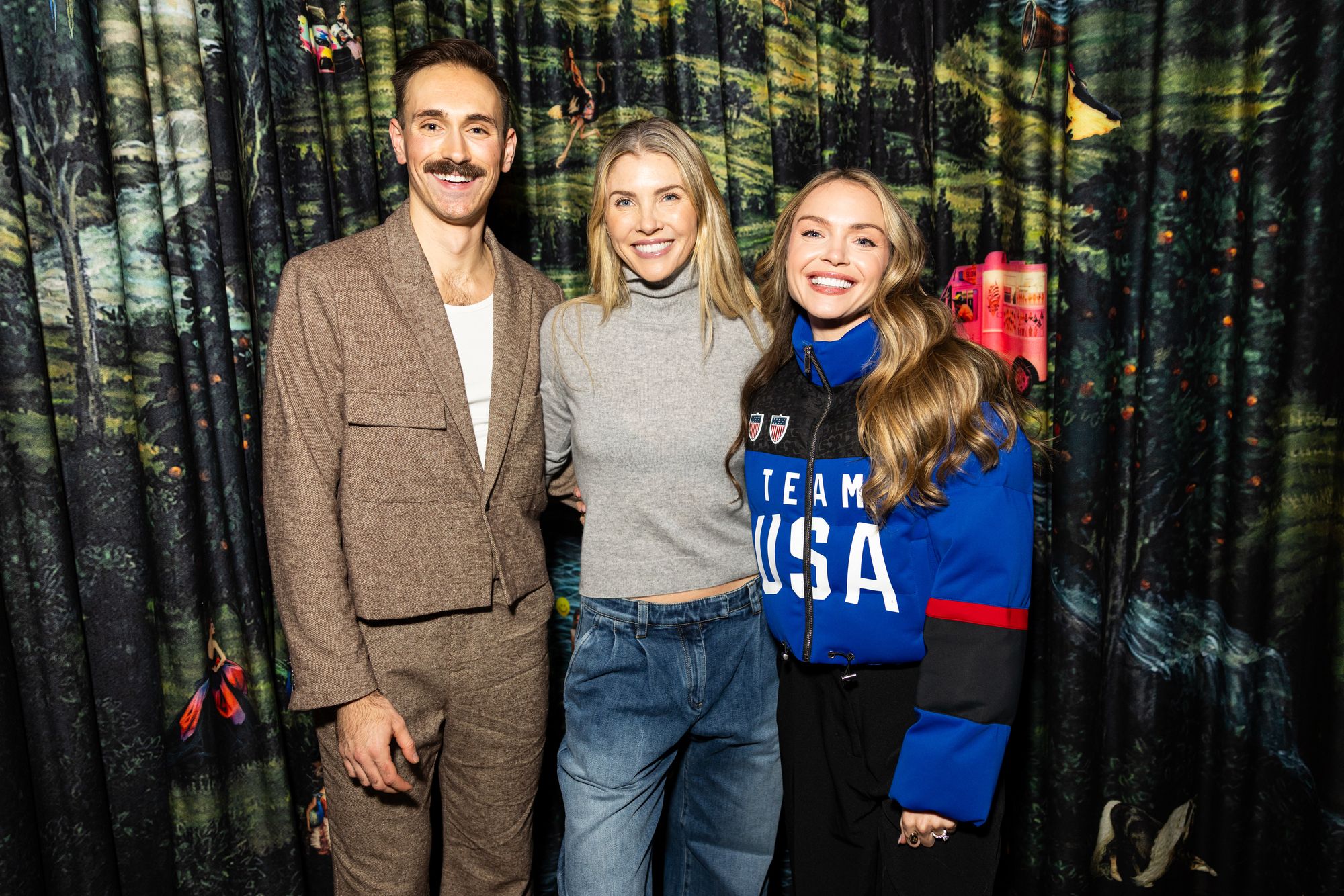 Three friends in Team USA gear pose together at an event step-and-repeat